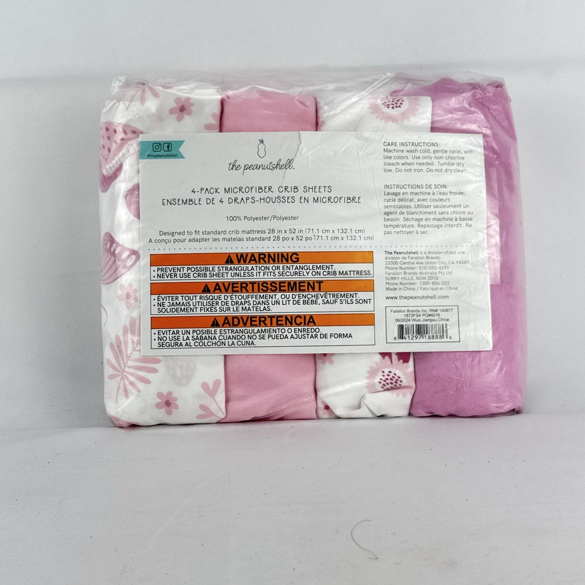 The Peanutshell 4-pack microfiber fitted crib sheets in pink floral and butterfly patterns, factory sealed packaging.