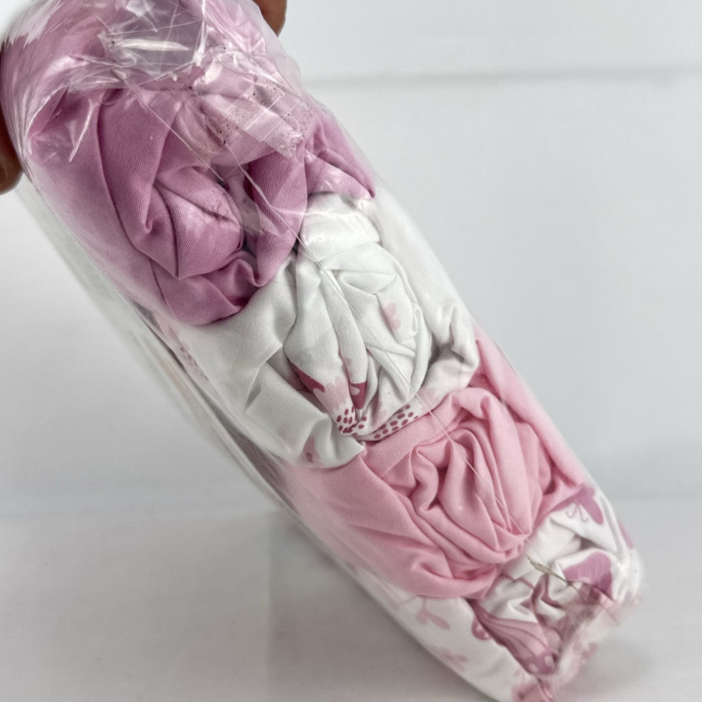 The Peanutshell 4-pack microfiber fitted crib sheets in pink floral and butterfly patterns, factory sealed packaging.