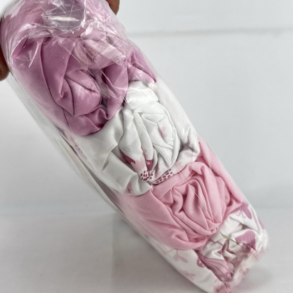 The Peanutshell 4-pack microfiber fitted crib sheets in pink floral and butterfly patterns, factory sealed packaging.