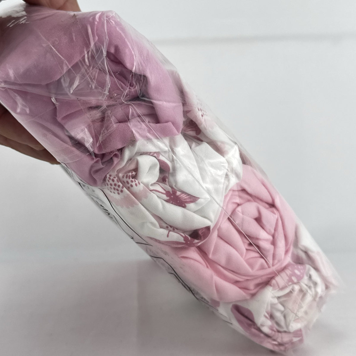 The Peanutshell 4-pack microfiber fitted crib sheets in pink floral and butterfly patterns, factory sealed packaging.