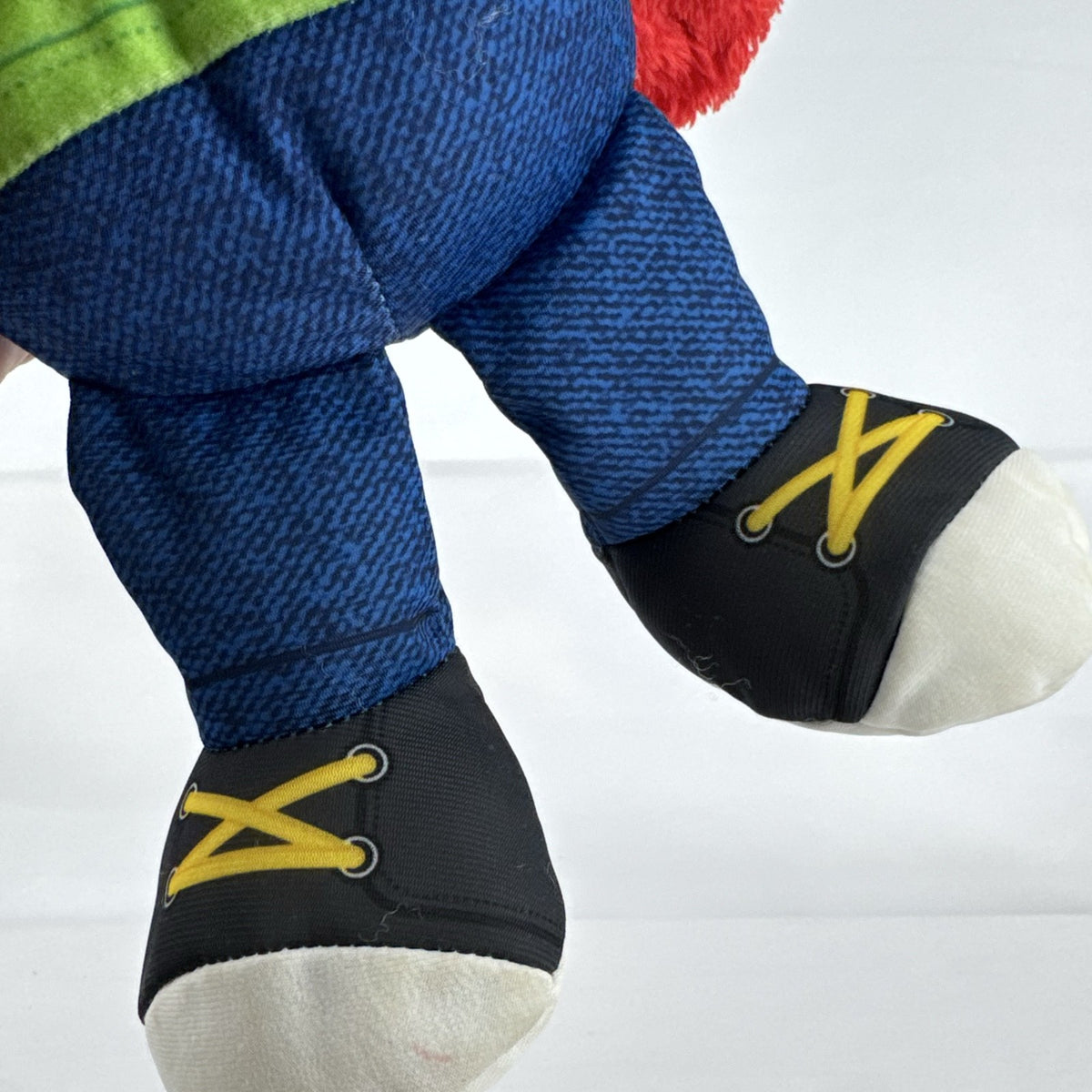 Hasbro Sesame Street ABC Elmo 12-inch plush toy wearing a colorblock alphabet shirt and sneakers.