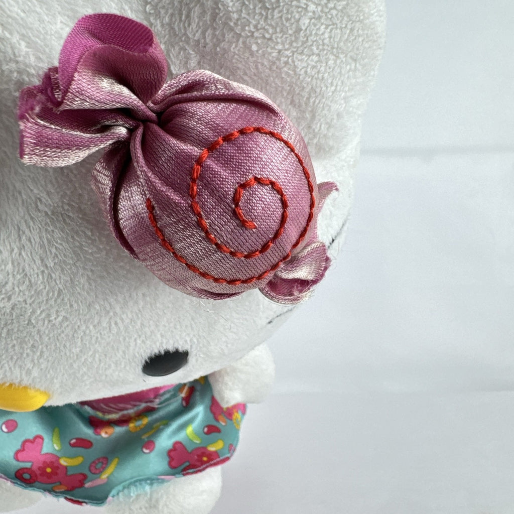 Sanrio Hello Kitty 9-inch plush doll wearing a teal candy print satin dress and holding a pink swirl lollipop.