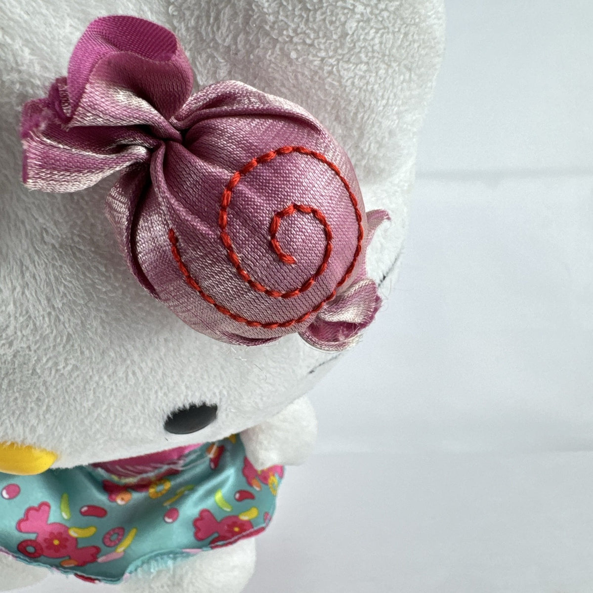 Sanrio Hello Kitty 9-inch plush doll wearing a teal candy print satin dress and holding a pink swirl lollipop.