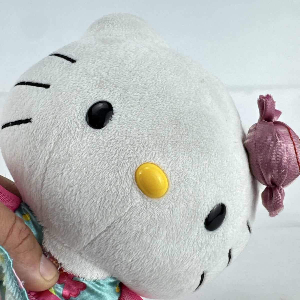 Sanrio Hello Kitty 9-inch plush doll wearing a teal candy print satin dress and holding a pink swirl lollipop.