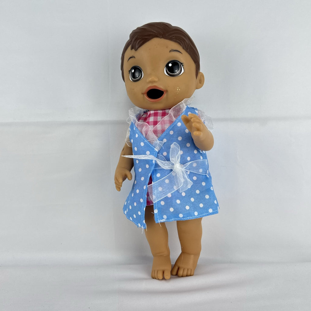 Hasbro Baby Alive 11-inch vinyl baby doll with molded brown hair, brown eyes, and blue polka dot dress