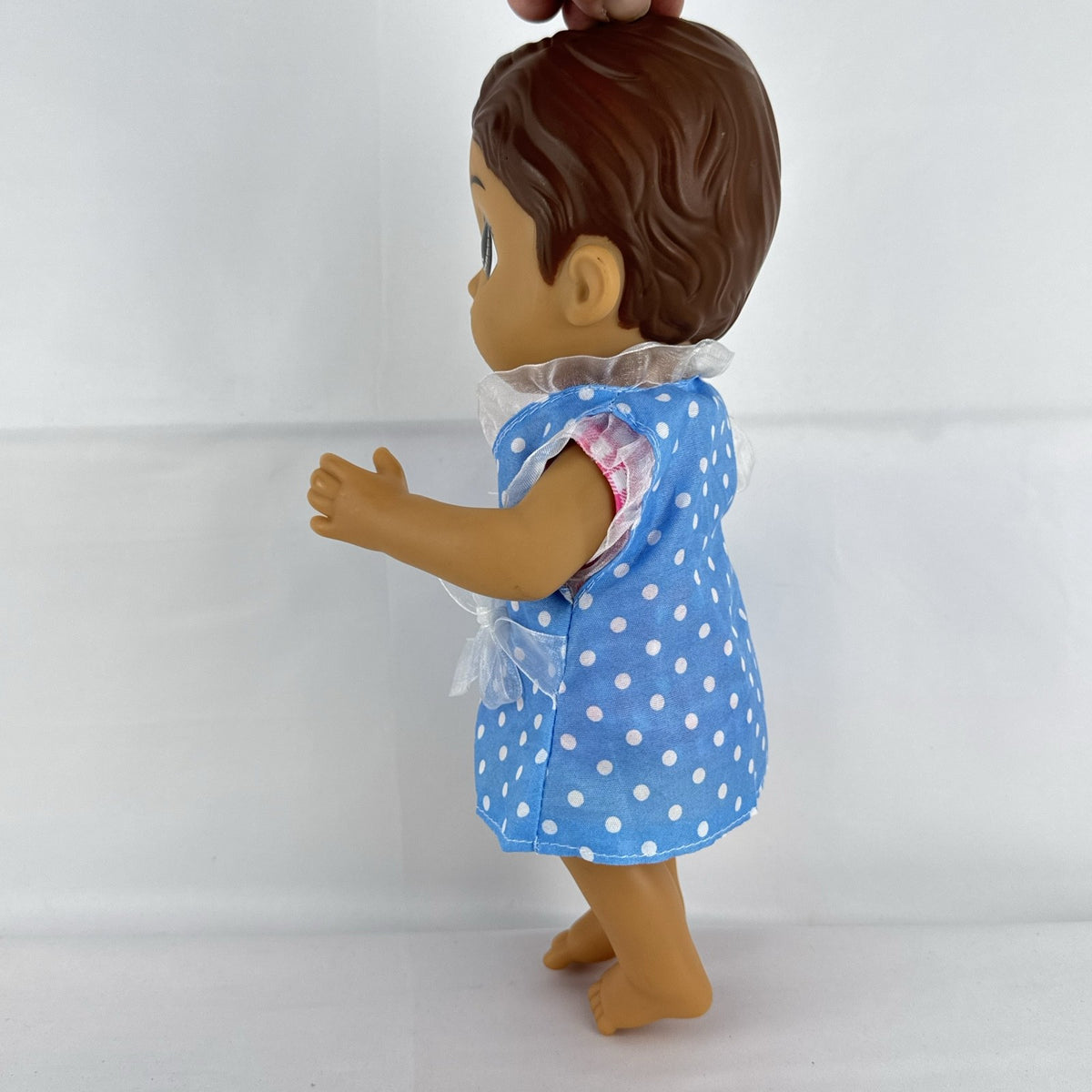 Hasbro Baby Alive 11-inch vinyl baby doll with molded brown hair, brown eyes, and blue polka dot dress