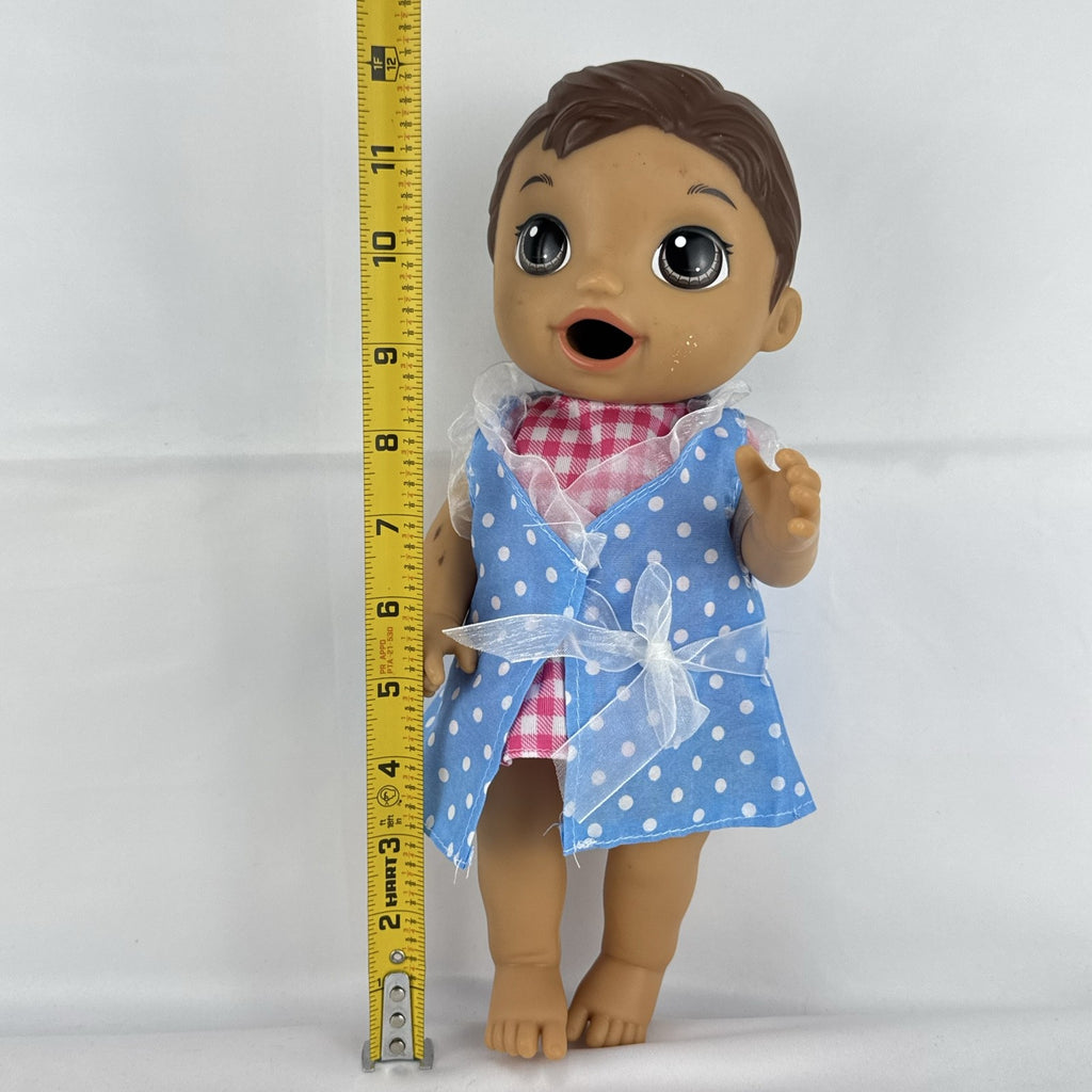 Hasbro Baby Alive 11-inch vinyl baby doll with molded brown hair, brown eyes, and blue polka dot dress