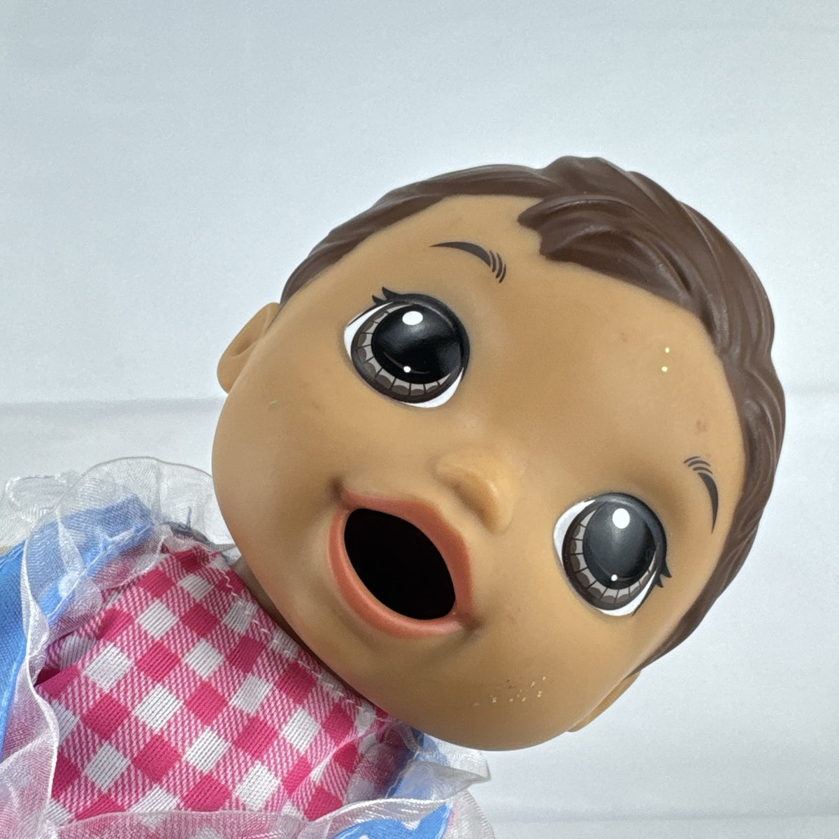 Hasbro Baby Alive 11-inch vinyl baby doll with molded brown hair, brown eyes, and blue polka dot dress