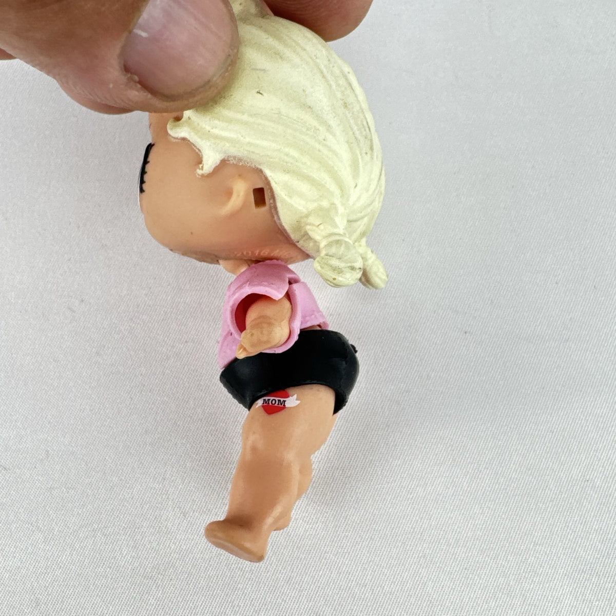 MGA L.O.L. Surprise! Biker Babe 3-inch doll with blonde sculpted hair, pink moto jacket, and MOM heart tattoo