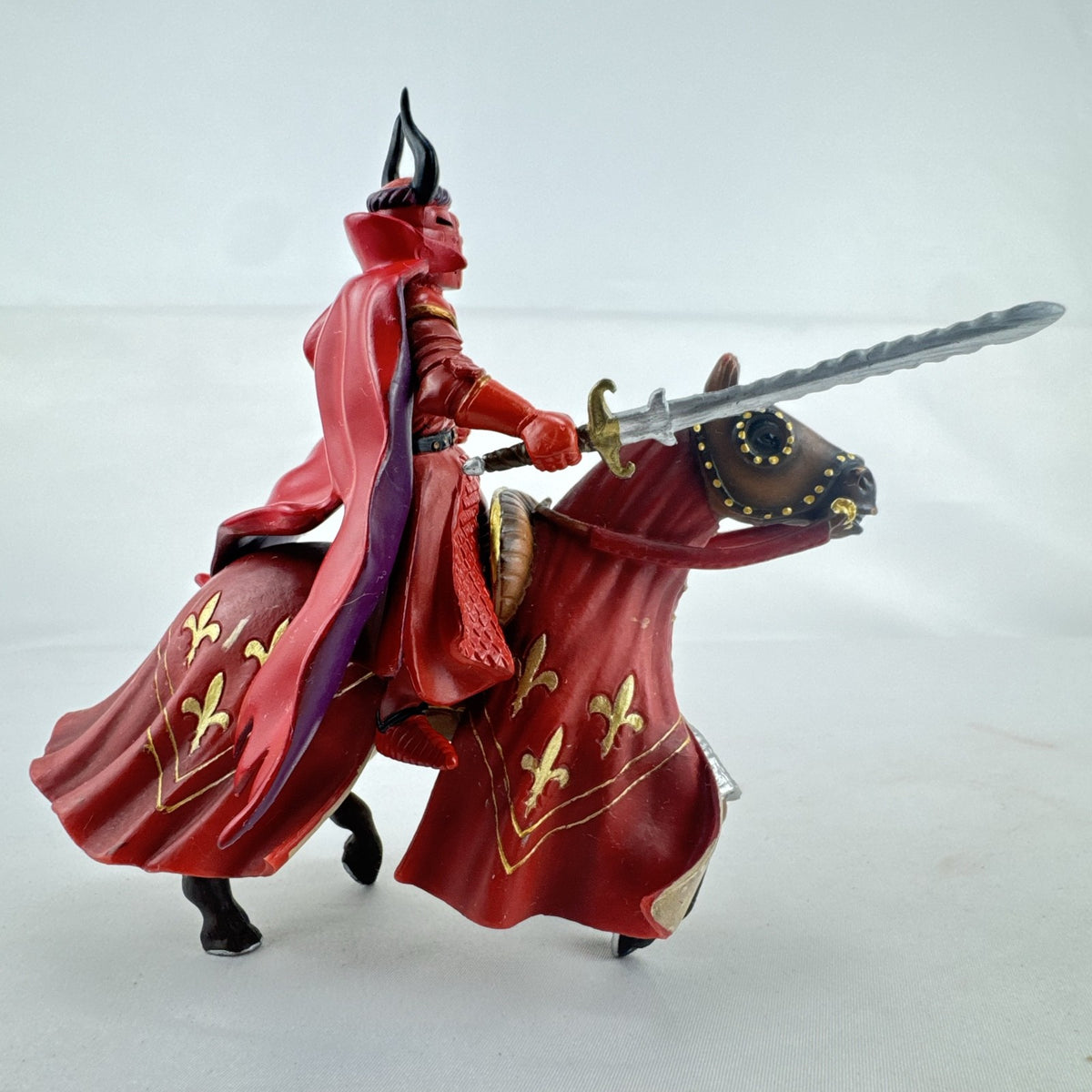 Papo red horned knight holding sword mounted on a Schleich crimson fleur-de-lis barded war horse