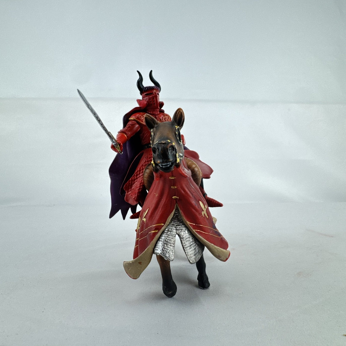 Papo red horned knight holding sword mounted on a Schleich crimson fleur-de-lis barded war horse