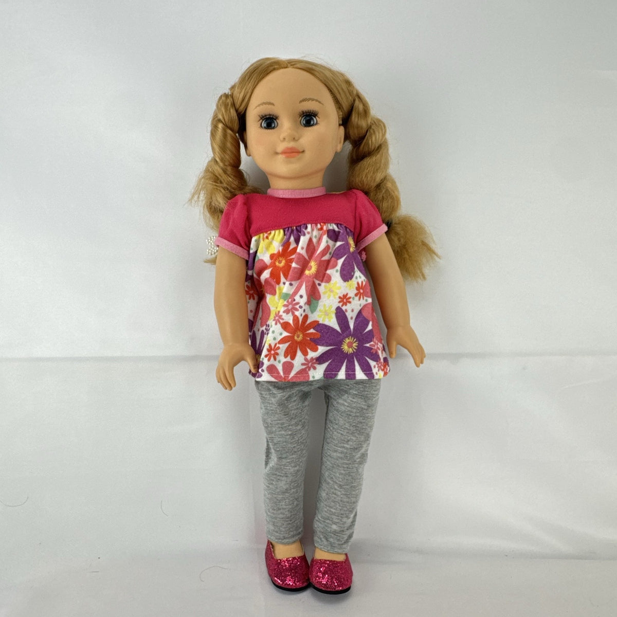 Lovee Doll & Toy Co. 18-inch girl doll with blonde braids, blue eyes, floral top, and pink glitter flats