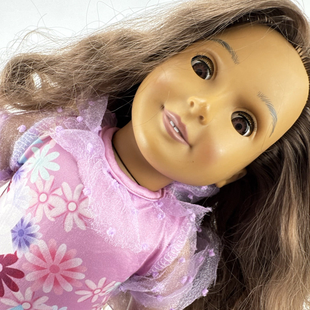 Battat Our Generation 18-inch girl doll with wavy brown hair wearing a pink floral tiered dress and bow shoes