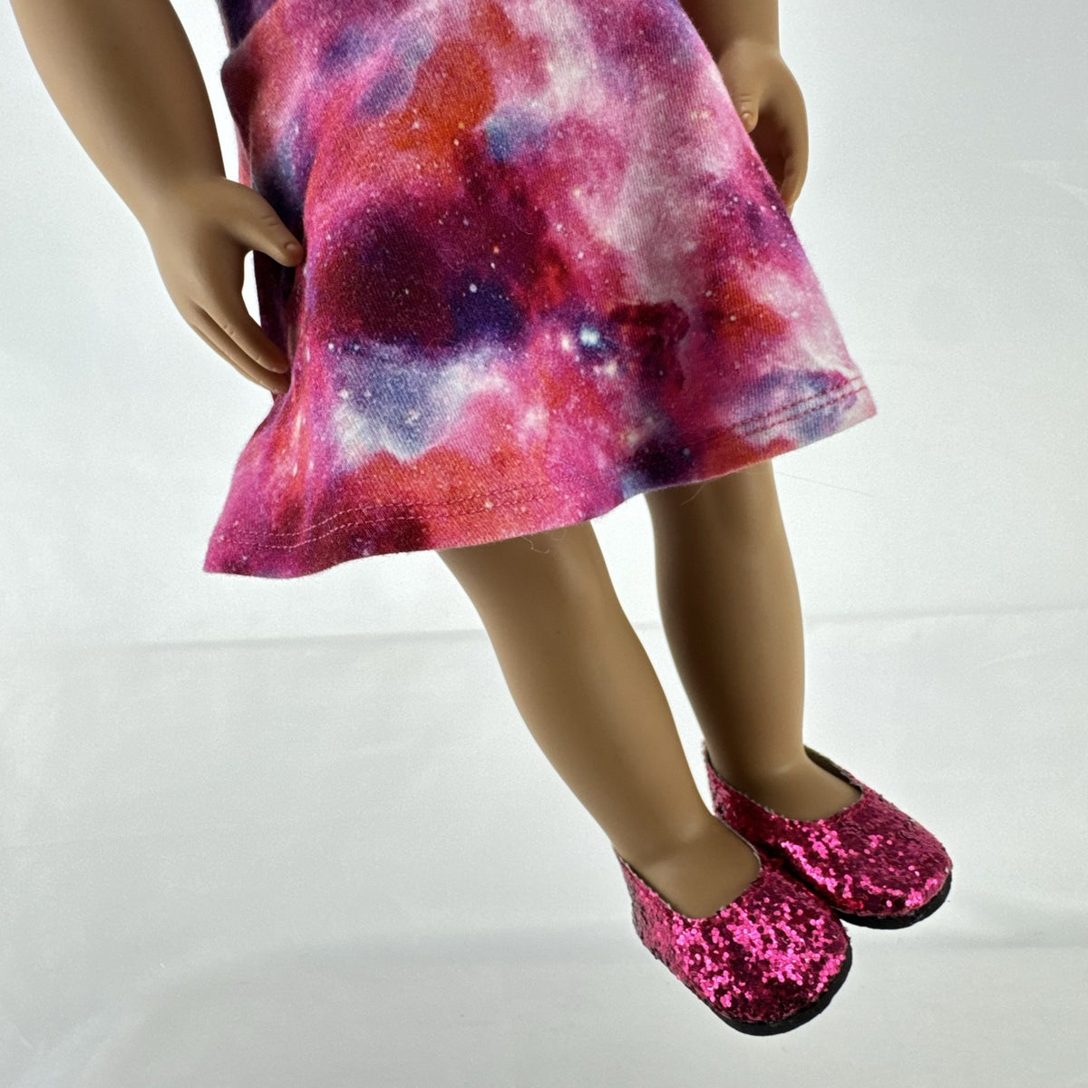 Our Generation 18-inch doll with brown afro puffs wearing a pink galaxy print dress and glitter shoes