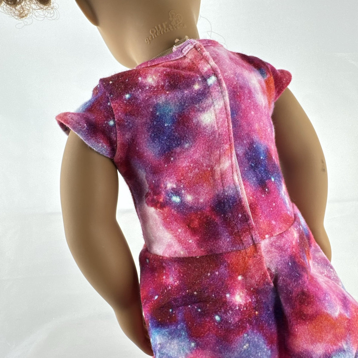 Our Generation 18-inch doll with brown afro puffs wearing a pink galaxy print dress and glitter shoes