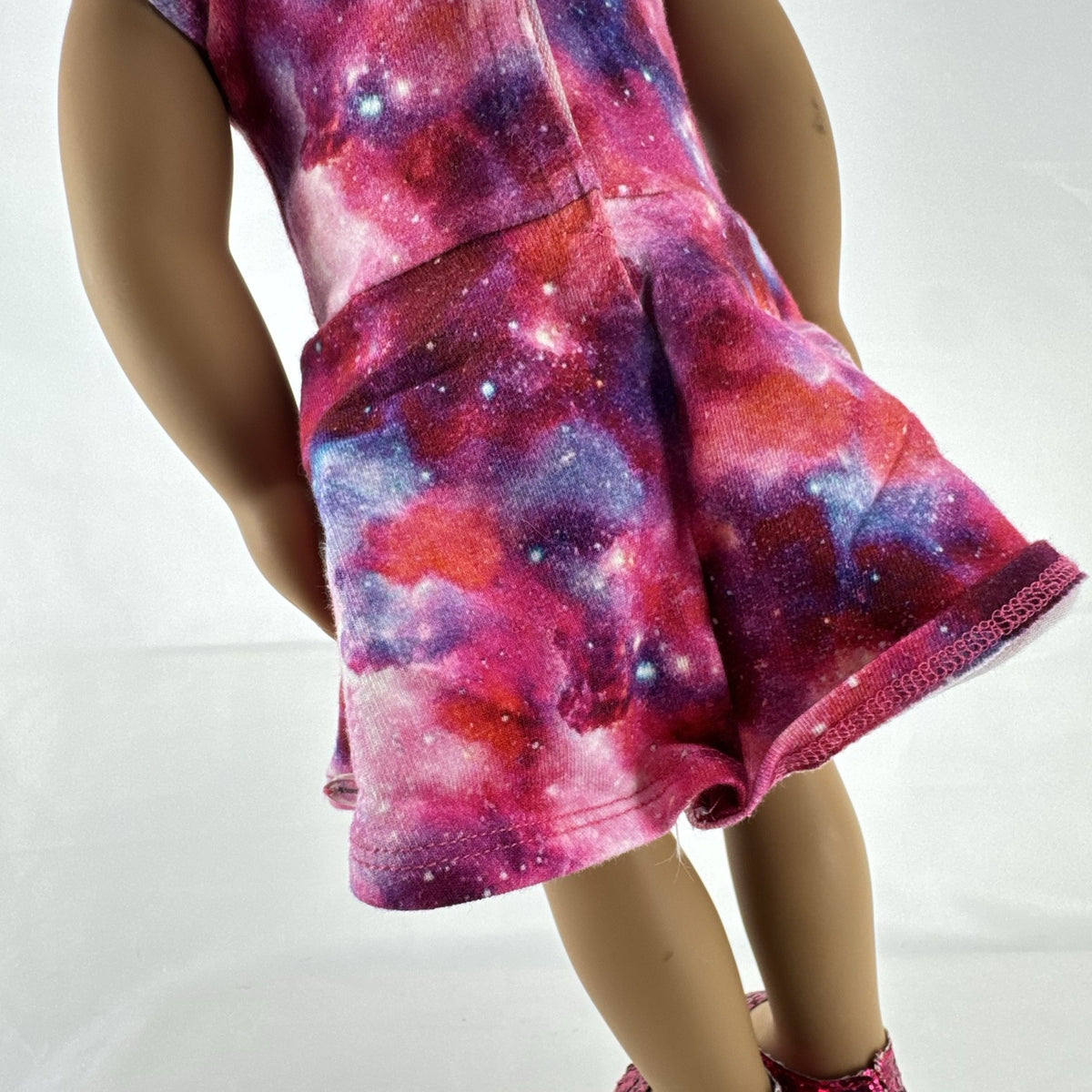Our Generation 18-inch doll with brown afro puffs wearing a pink galaxy print dress and glitter shoes