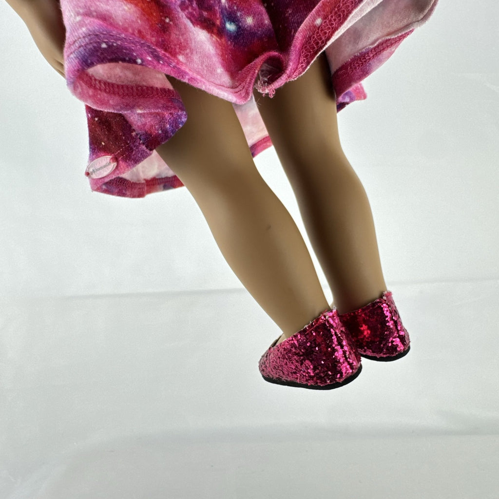 Our Generation 18-inch doll with brown afro puffs wearing a pink galaxy print dress and glitter shoes