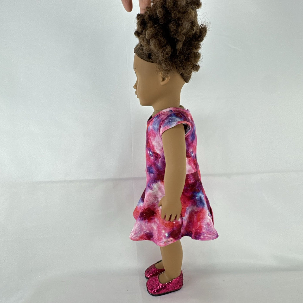 Our Generation 18-inch doll with brown afro puffs wearing a pink galaxy print dress and glitter shoes