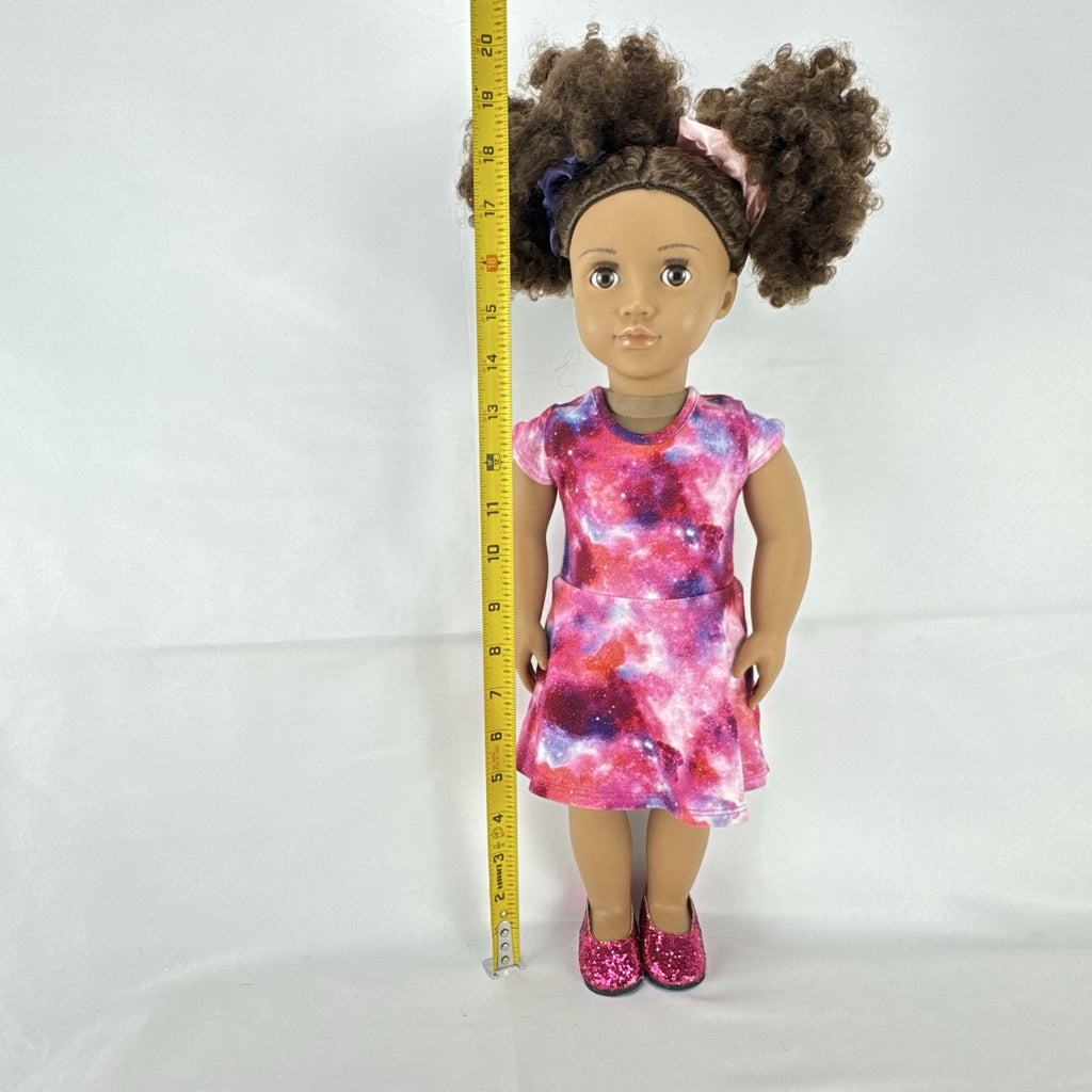 Our Generation 18-inch doll with brown afro puffs wearing a pink galaxy print dress and glitter shoes