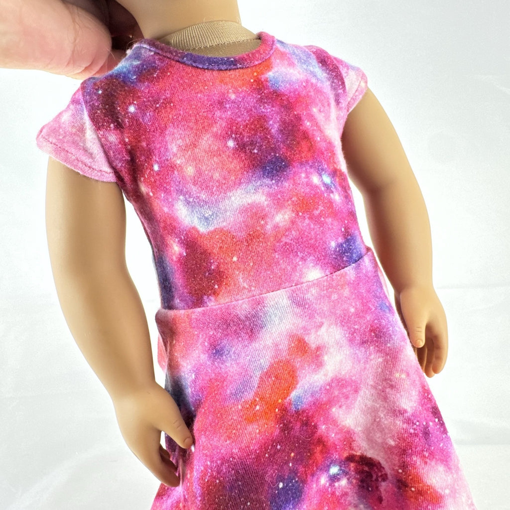 Our Generation 18-inch doll with brown afro puffs wearing a pink galaxy print dress and glitter shoes