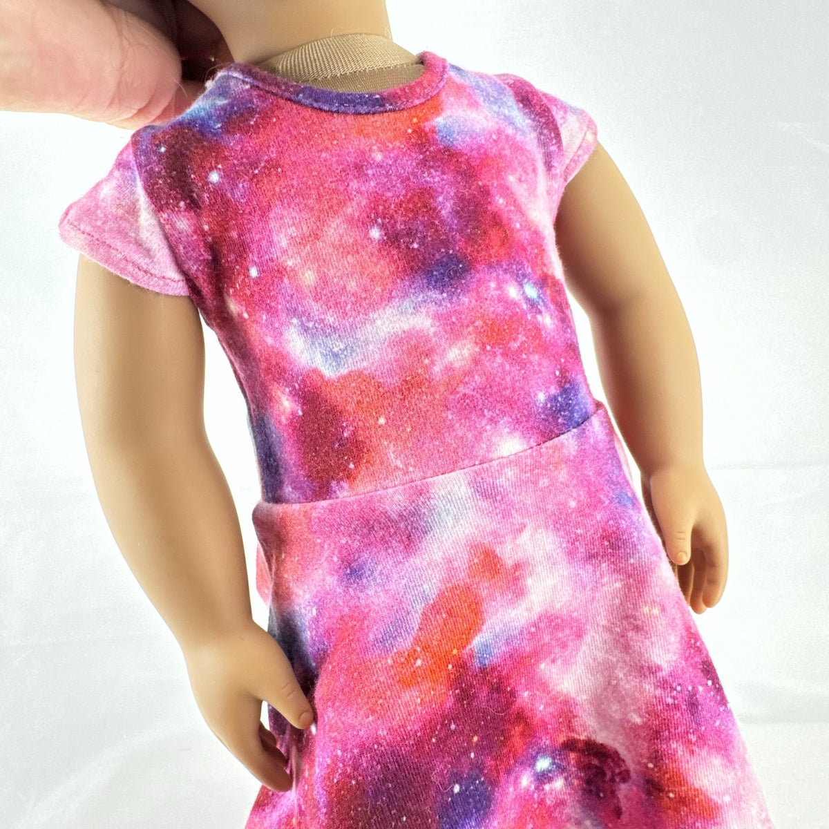 Our Generation 18-inch doll with brown afro puffs wearing a pink galaxy print dress and glitter shoes