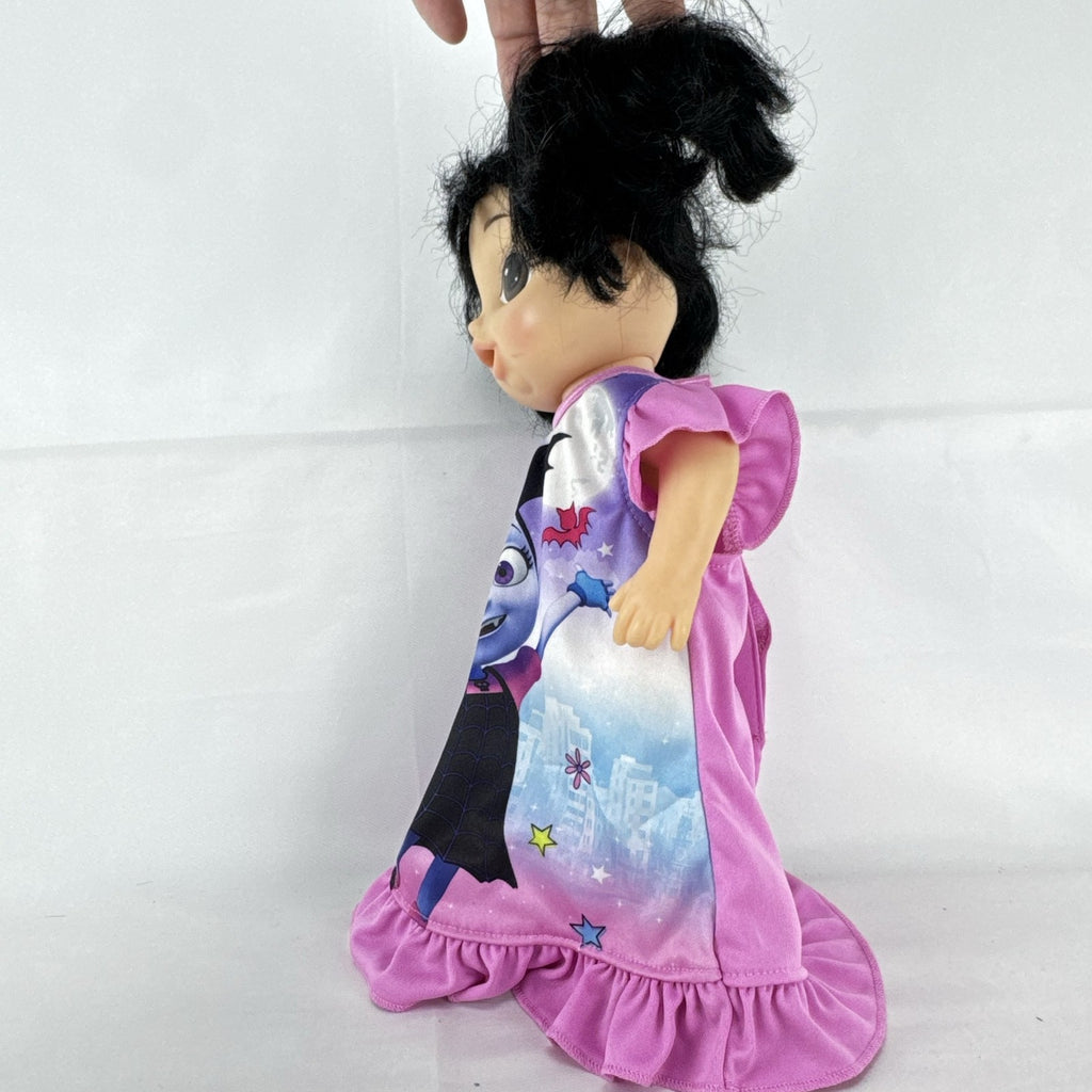 Hasbro Baby Alive 12-inch doll with black pigtails wearing a colorful Disney Vampirina dress