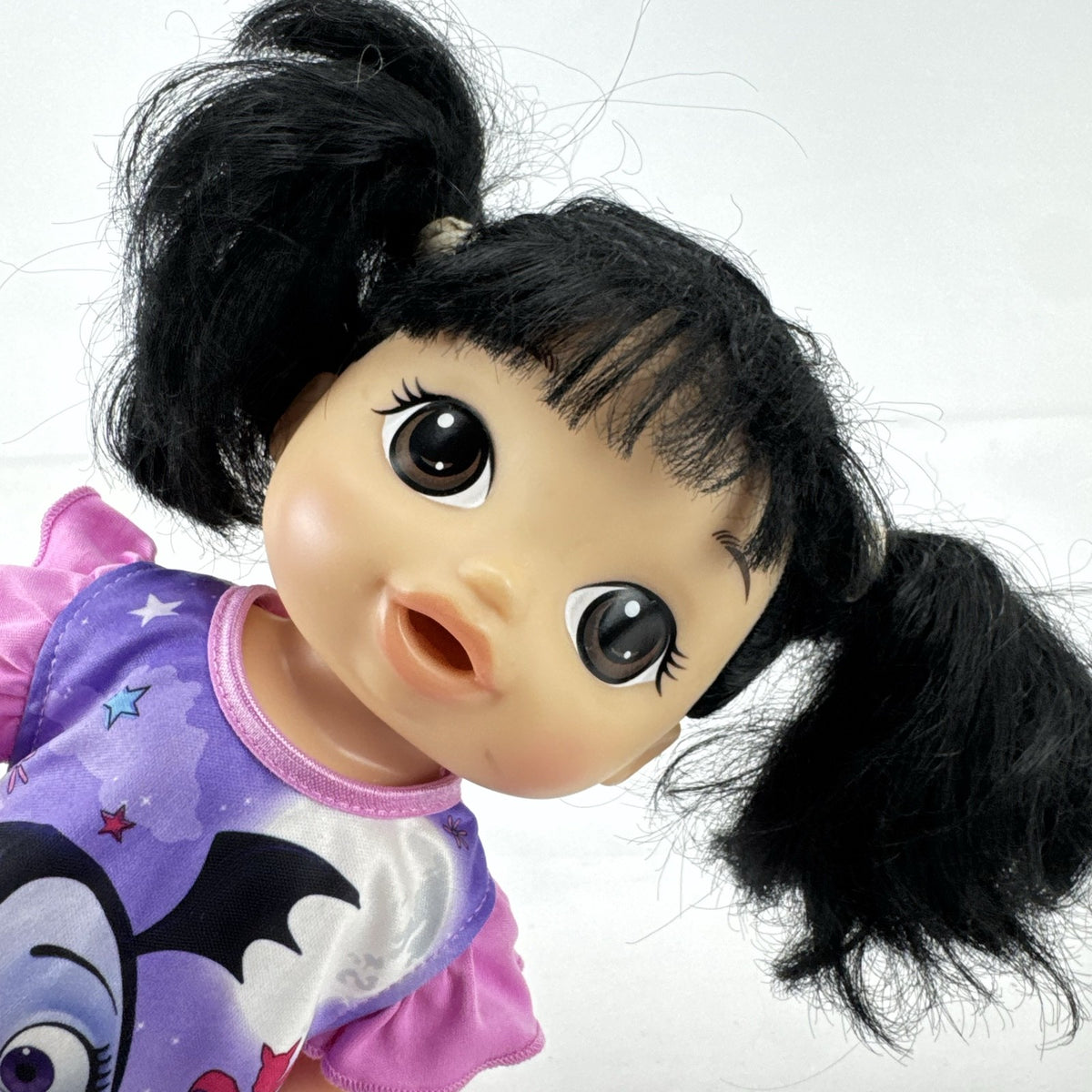 Hasbro Baby Alive 12-inch doll with black pigtails wearing a colorful Disney Vampirina dress