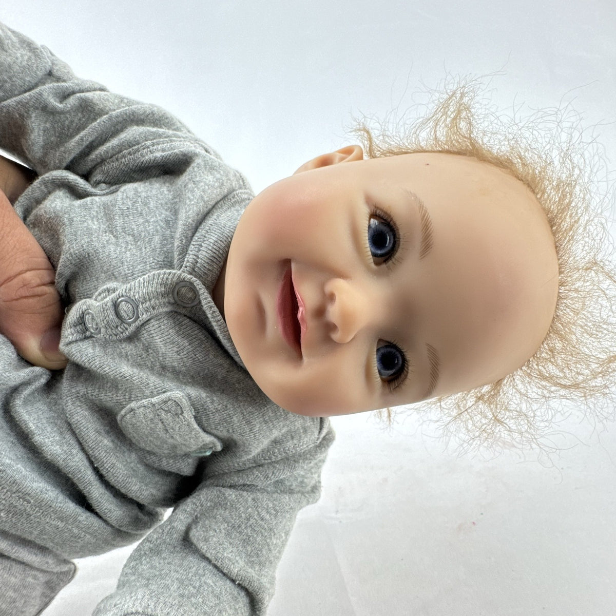 The Ashton-Drake Galleries 16-inch vinyl reborn baby doll sculpted by Ping Lau in grey loungewear
