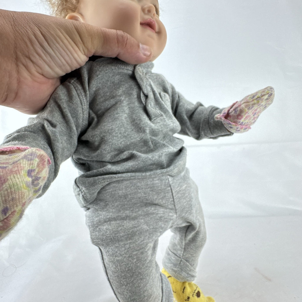 The Ashton-Drake Galleries 16-inch vinyl reborn baby doll sculpted by Ping Lau in grey loungewear