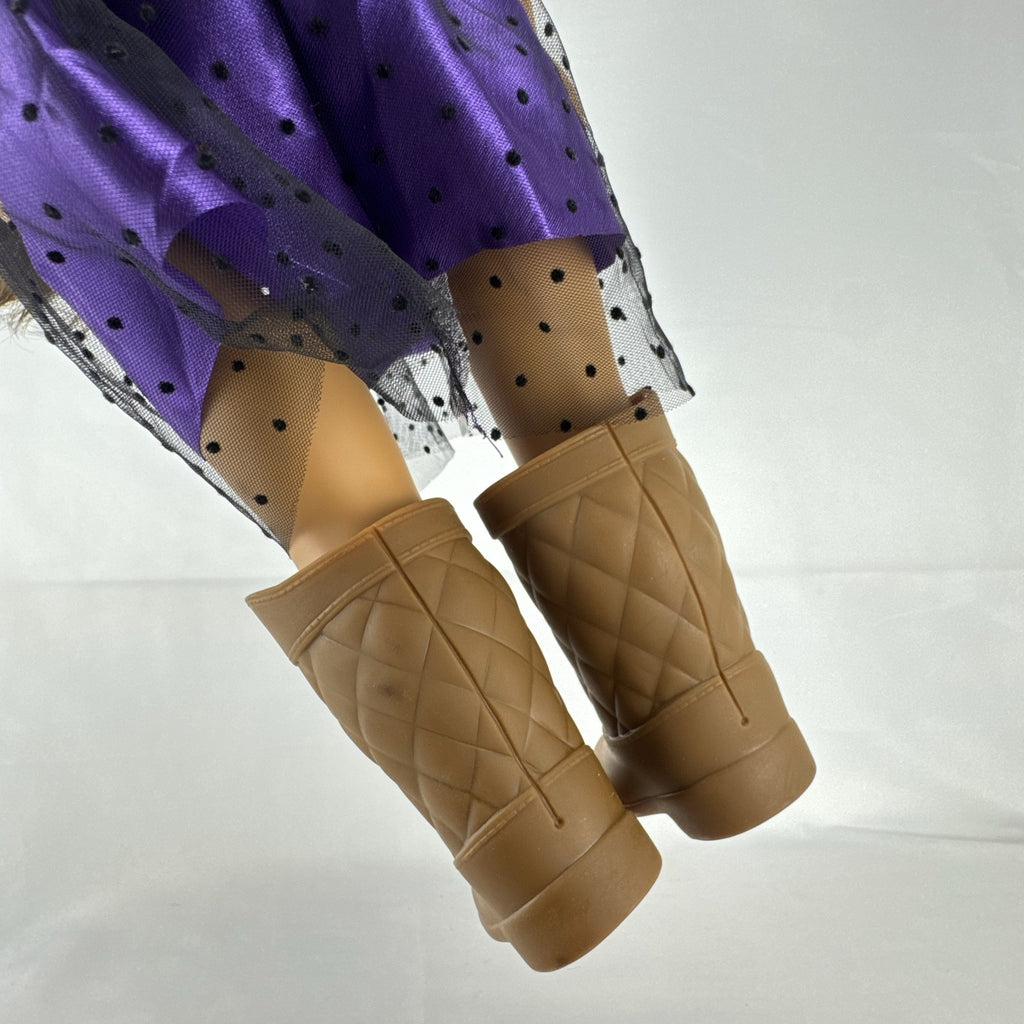 Battat Our Generation 18-inch vinyl doll with wavy dark brown hair, wearing a purple polka-dot dress and tan boots.