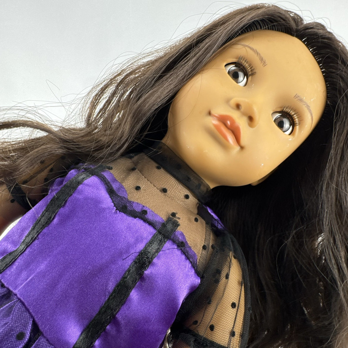 Battat Our Generation 18-inch vinyl doll with wavy dark brown hair, wearing a purple polka-dot dress and tan boots.