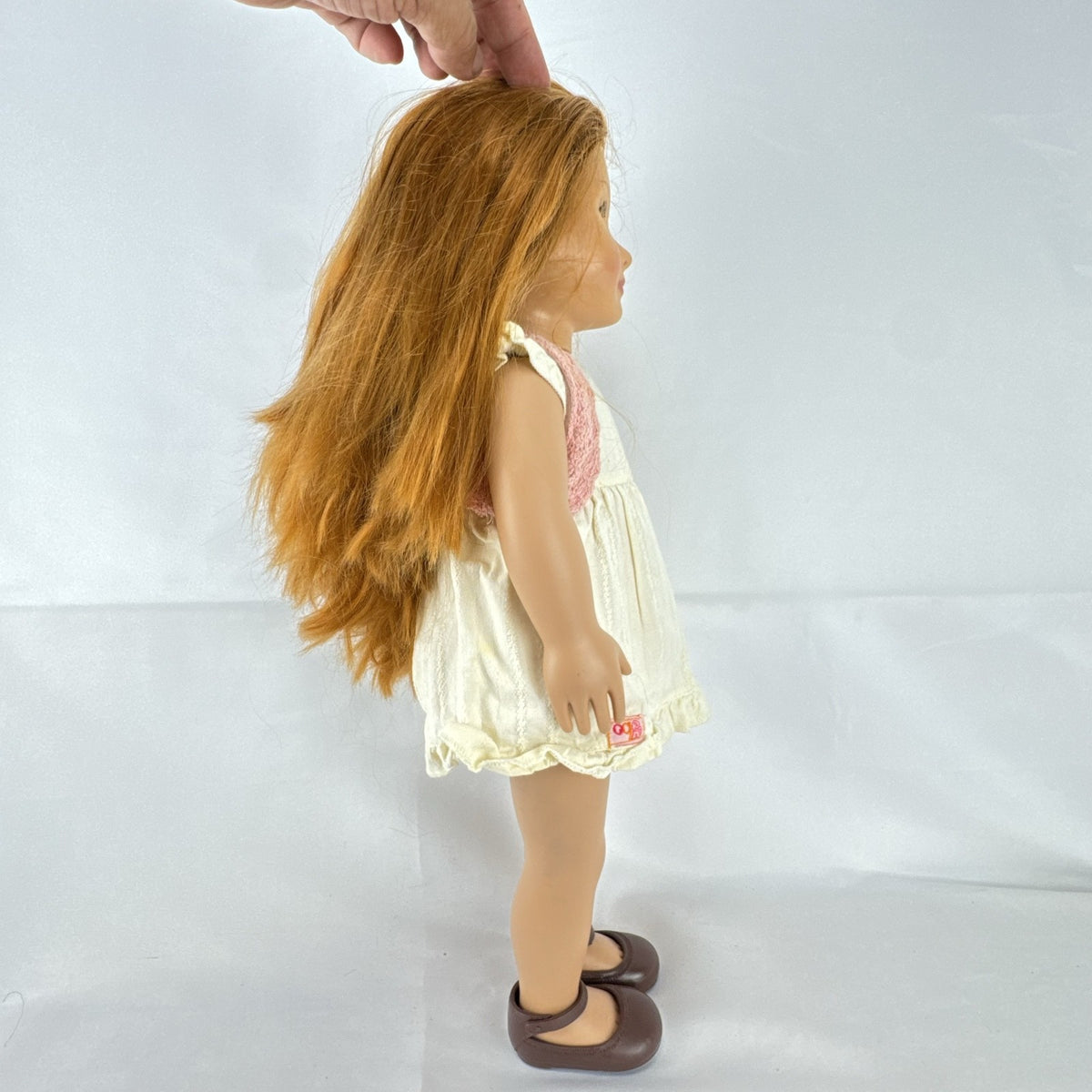 Battat Our Generation 18-inch doll with auburn hair and green eyes wearing cream ruffle dress and pink shrug