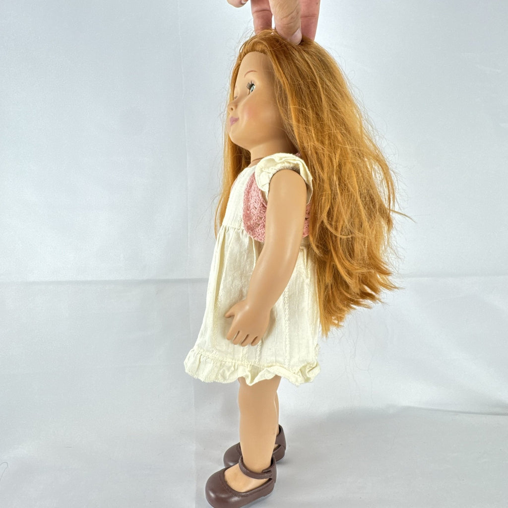 Battat Our Generation 18-inch doll with auburn hair and green eyes wearing cream ruffle dress and pink shrug