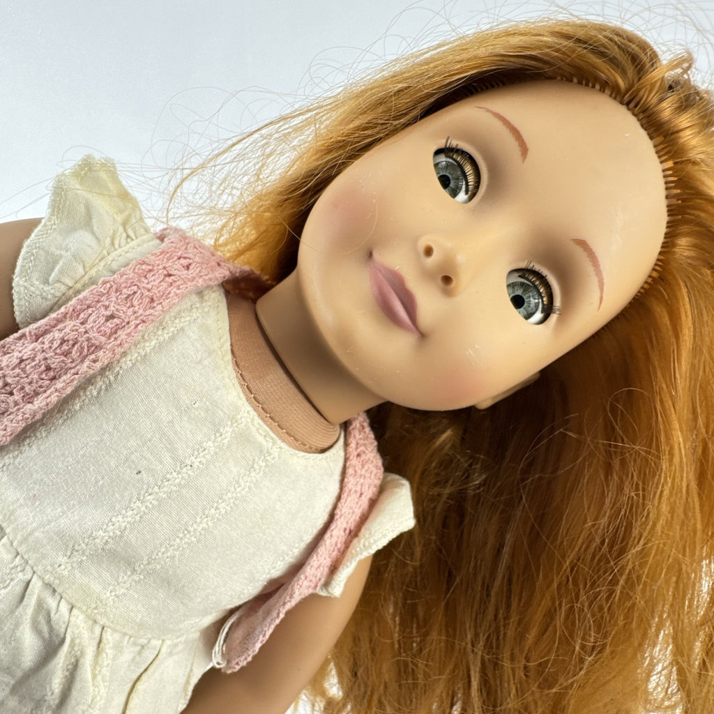 Battat Our Generation 18-inch doll with auburn hair and green eyes wearing cream ruffle dress and pink shrug