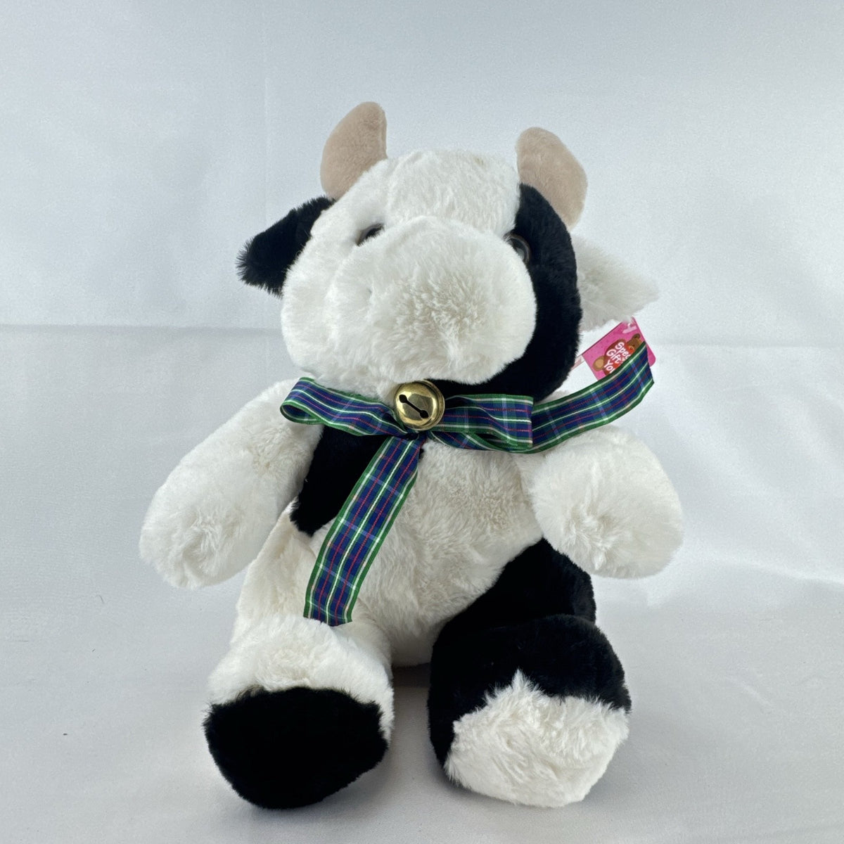 Star Gifts 13-inch black and white Holstein cow plush wearing a green plaid ribbon and jingle bell