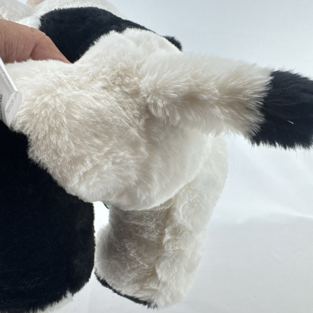 Star Gifts 13-inch black and white Holstein cow plush wearing a green plaid ribbon and jingle bell