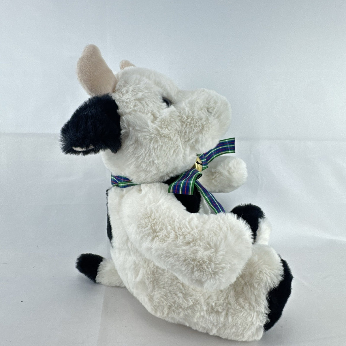 Star Gifts 13-inch black and white Holstein cow plush wearing a green plaid ribbon and jingle bell