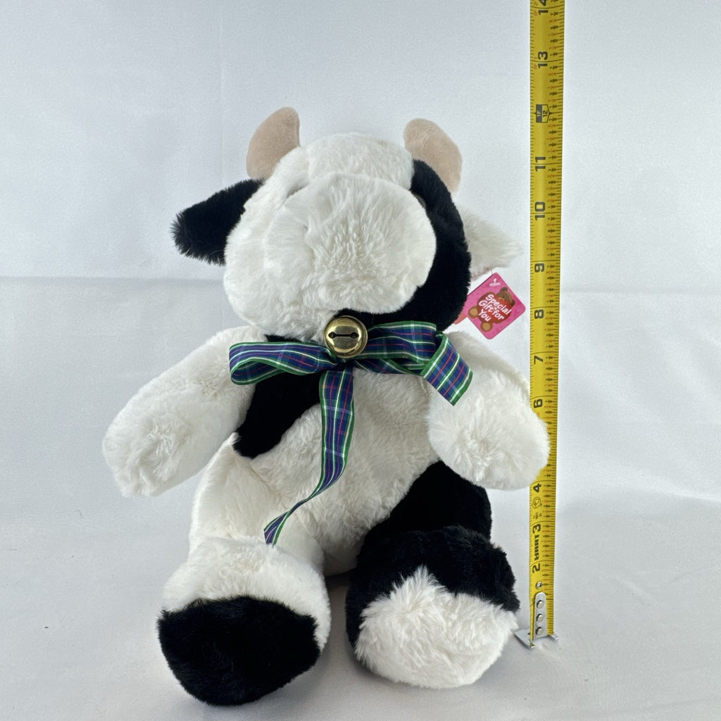 Star Gifts 13-inch black and white Holstein cow plush wearing a green plaid ribbon and jingle bell