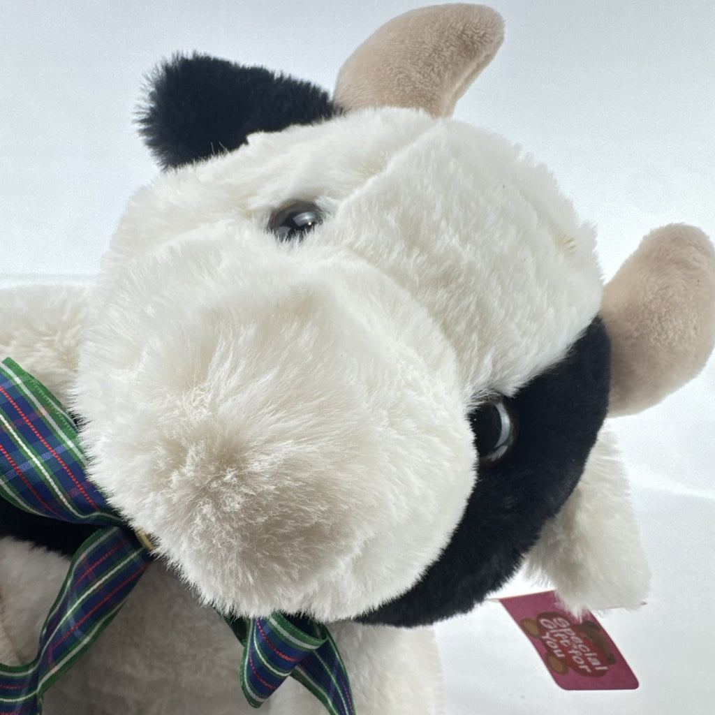 Star Gifts 13-inch black and white Holstein cow plush wearing a green plaid ribbon and jingle bell
