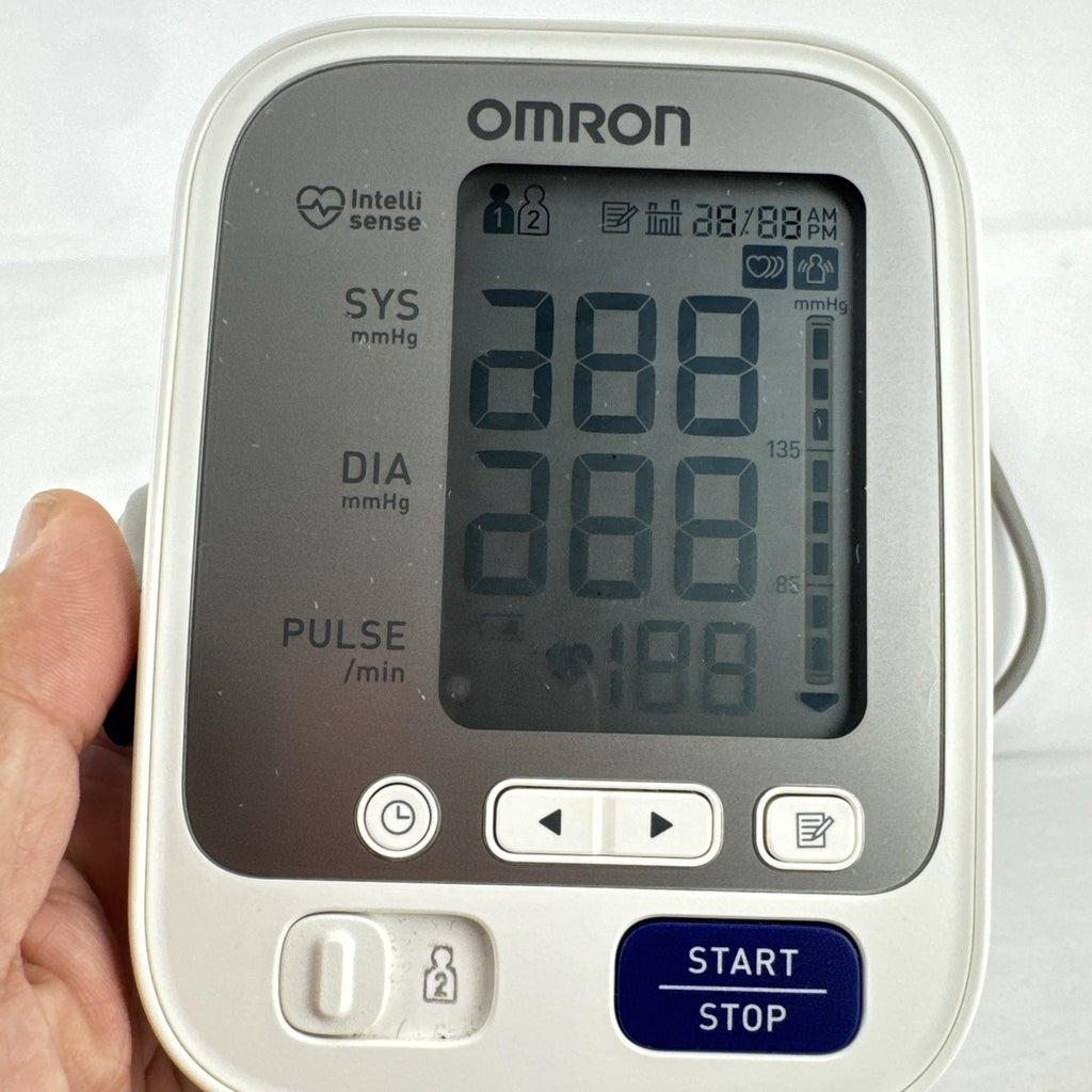 White Omron upper arm blood pressure monitor with digital LCD display and adjustable wide fabric cuff