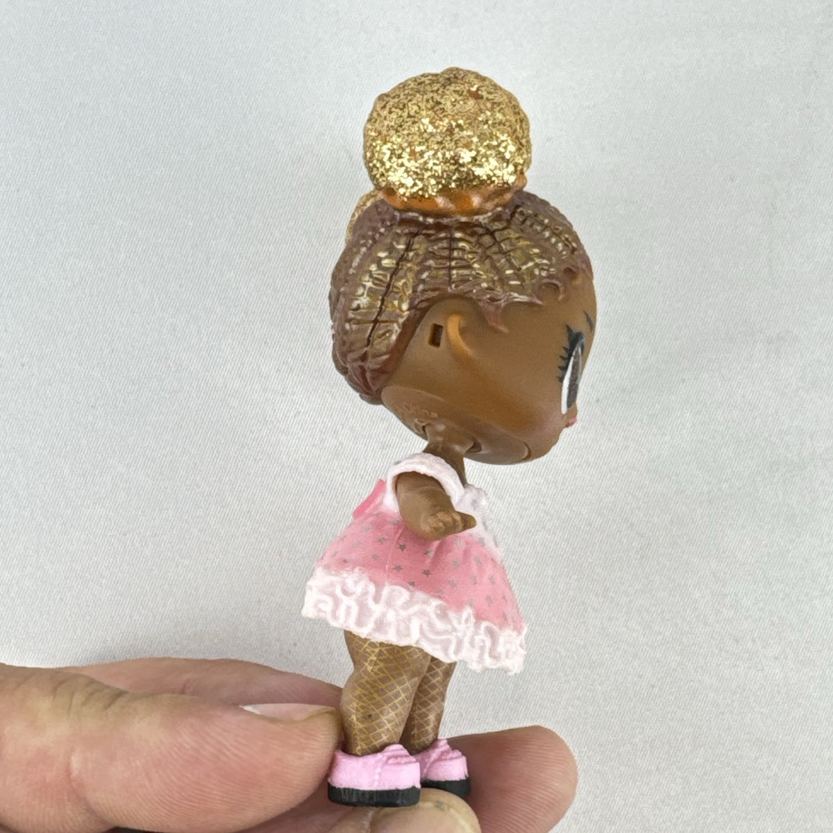 MGA Entertainment L.O.L. Surprise Glitter Series Queen Bee doll with gold glitter hair buns, pink dress, and shoes