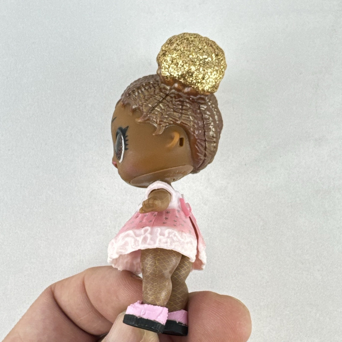 MGA Entertainment L.O.L. Surprise Glitter Series Queen Bee doll with gold glitter hair buns, pink dress, and shoes