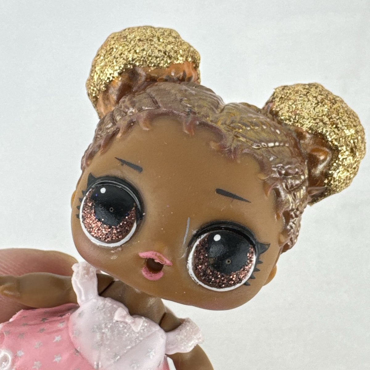 MGA Entertainment L.O.L. Surprise Glitter Series Queen Bee doll with gold glitter hair buns, pink dress, and shoes