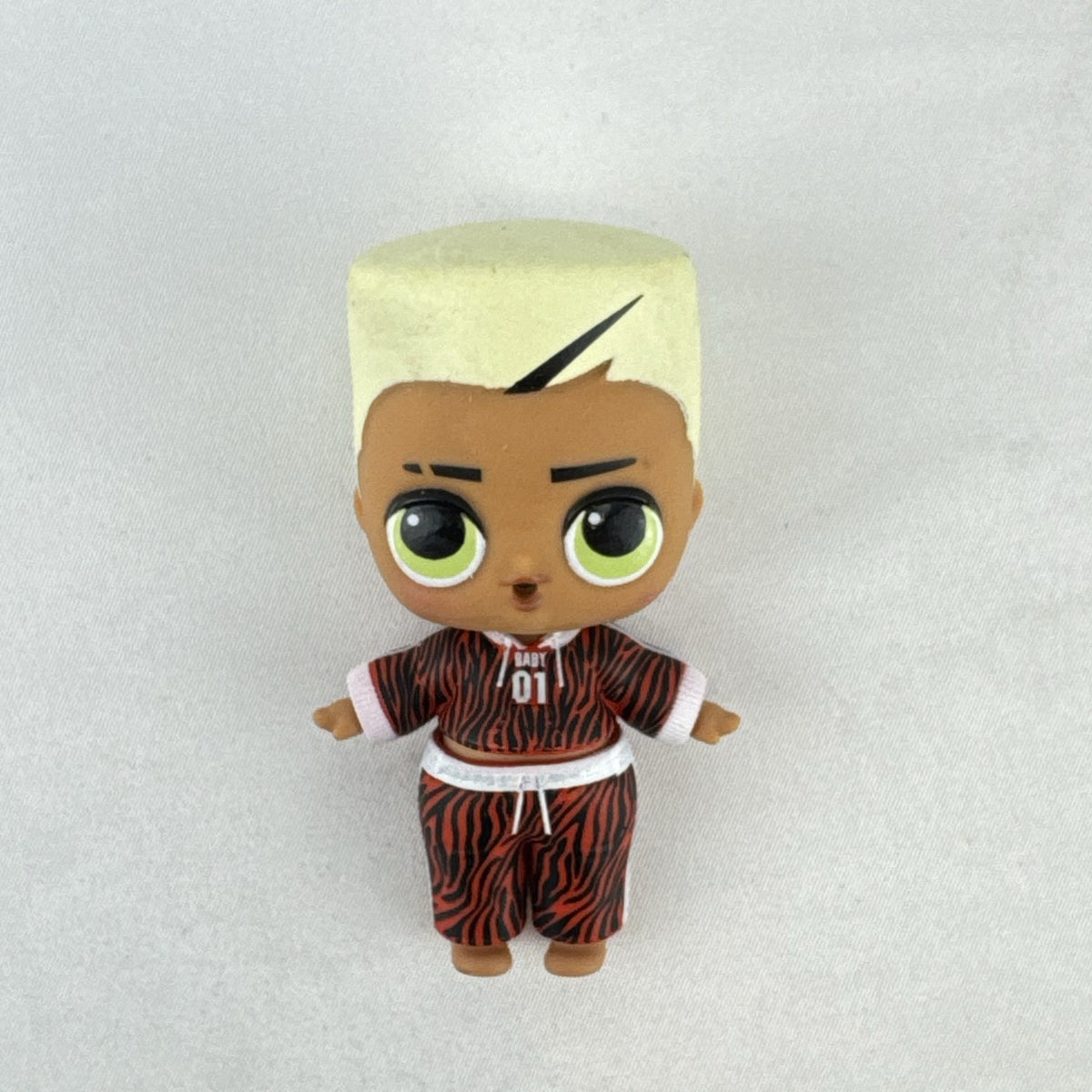 MGA L.O.L. Surprise Boys Swaggy 3-inch mini doll with blonde flocked hair and red tracksuit.