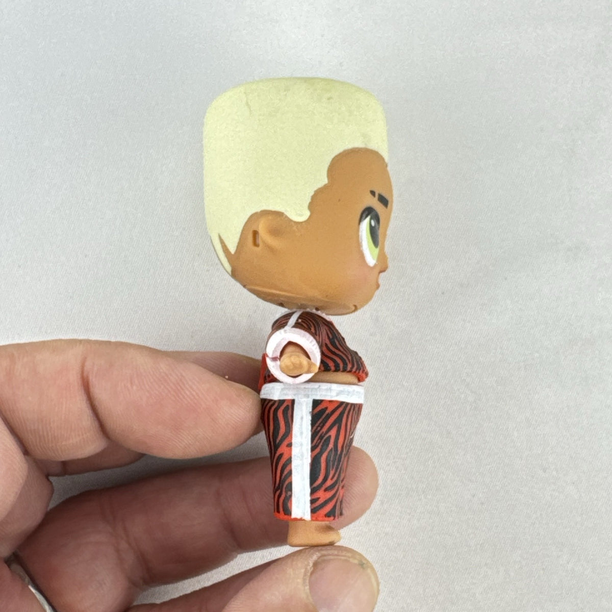 MGA L.O.L. Surprise Boys Swaggy 3-inch mini doll with blonde flocked hair and red tracksuit.
