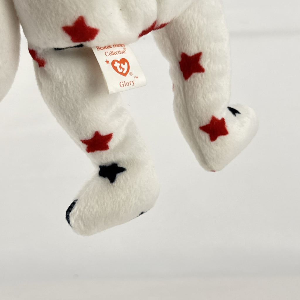 Ty Beanie Baby Glory bear plush featuring patriotic red and navy blue stars and an embroidered American flag