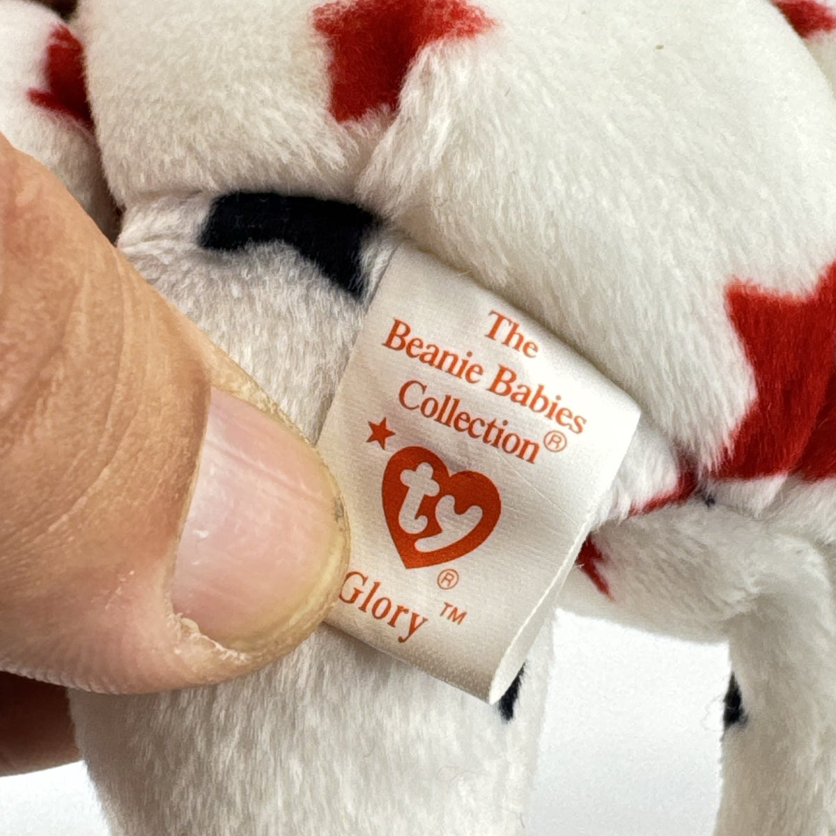 Ty Beanie Baby Glory bear plush featuring patriotic red and navy blue stars and an embroidered American flag