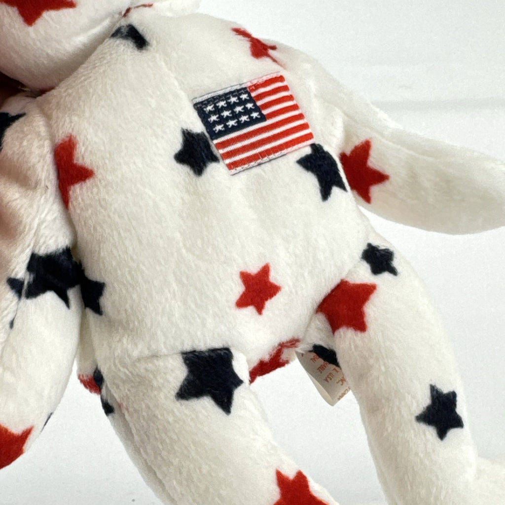 Ty Beanie Baby Glory bear plush featuring patriotic red and navy blue stars and an embroidered American flag