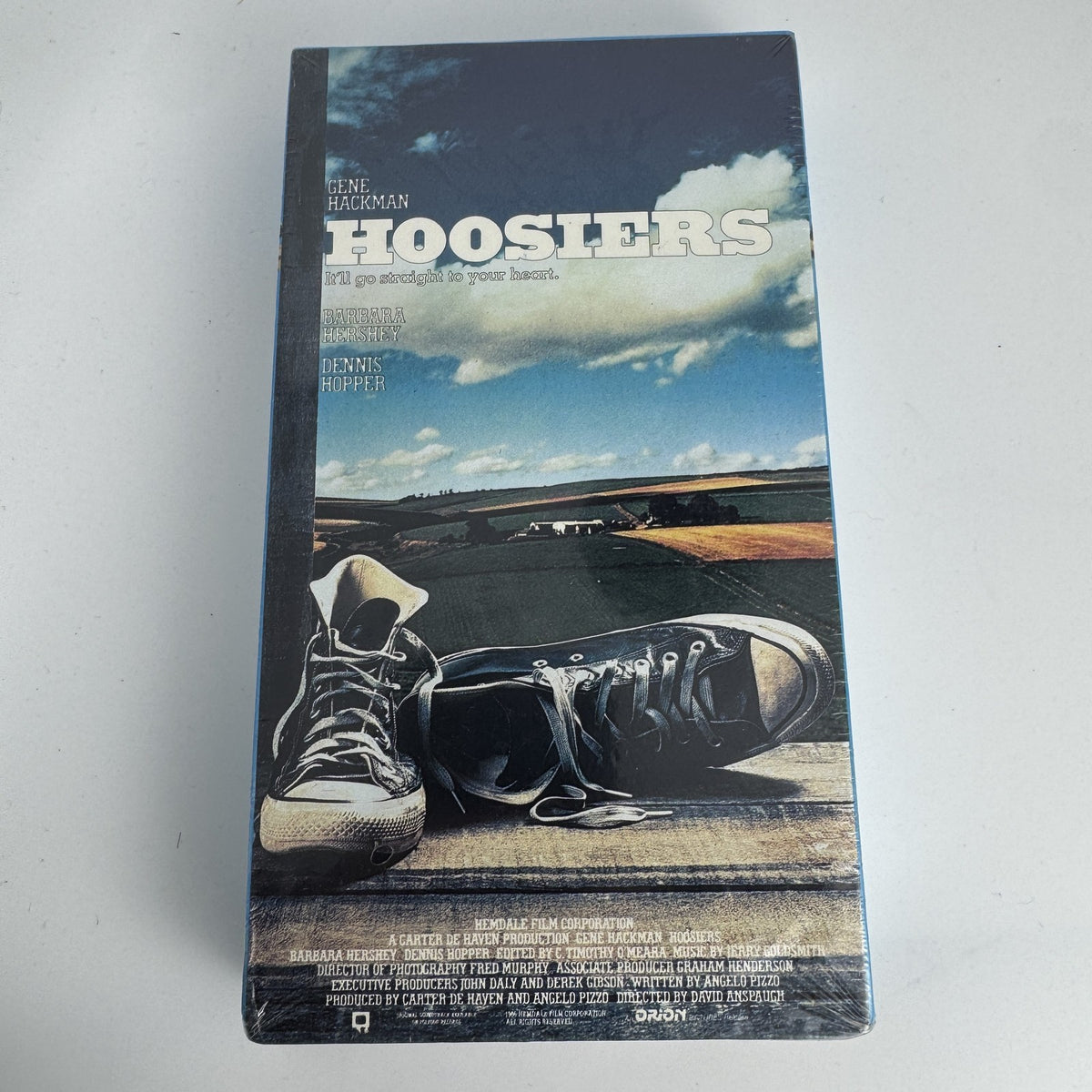 Four factory sealed vintage VHS tapes including Hoosiers, James Bond 007, Sports Illustrated 1993, and Chrysler promo.